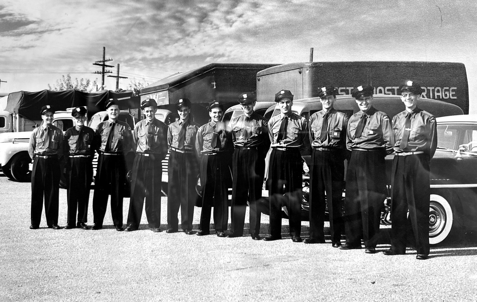 West Coast Cartage drivers in uniform lined up in front of the fleet